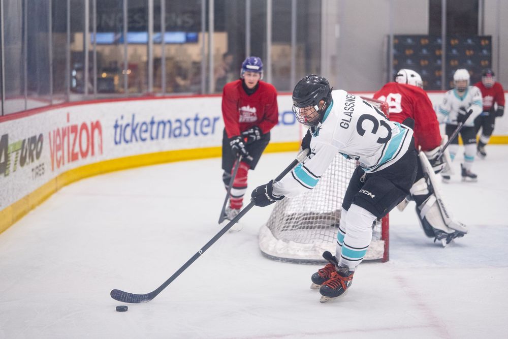 A hockey player in blue and white fights takes control of the puck near the goal they try to score on