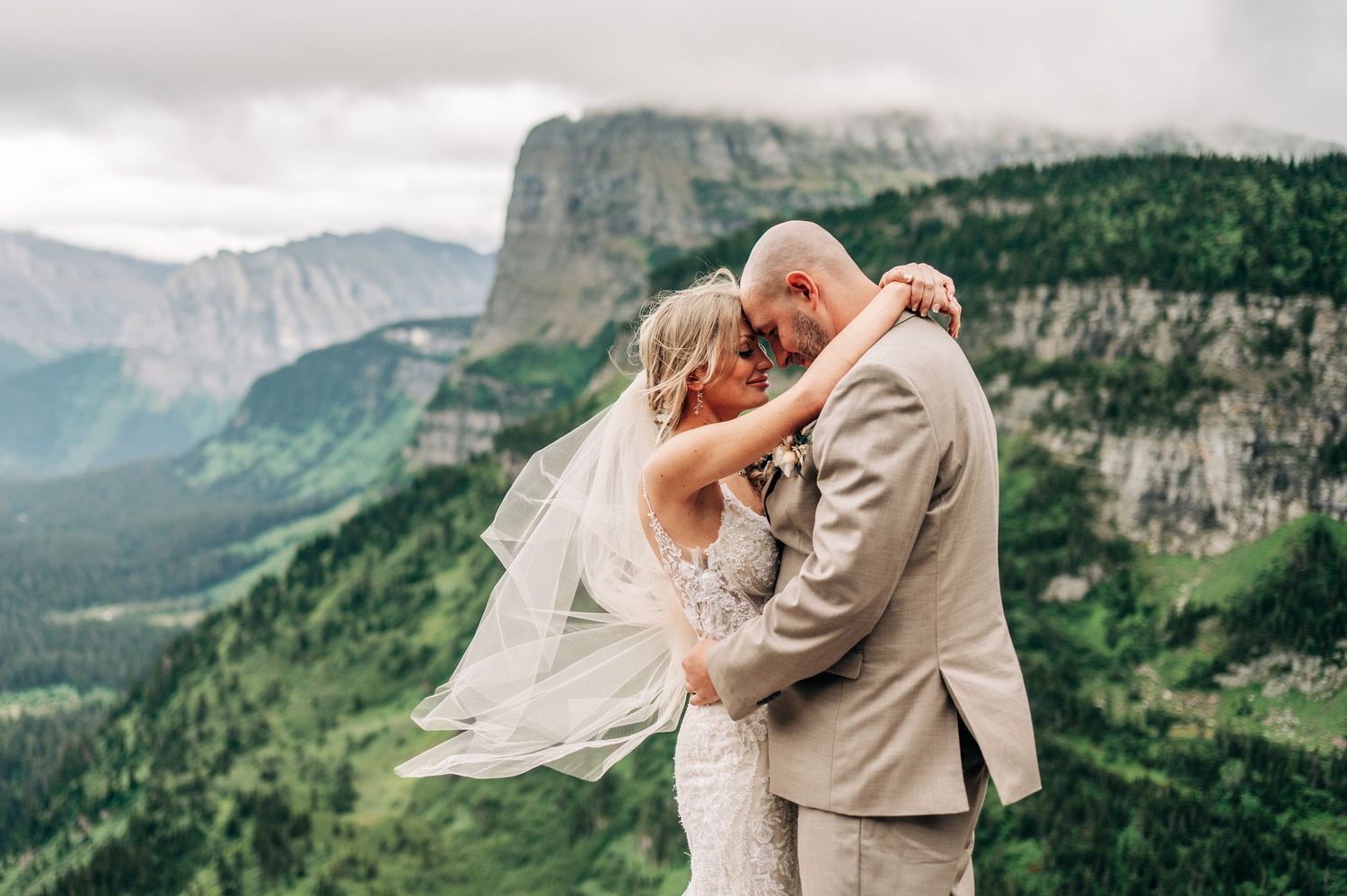 A couple shares romantic moments in front of majestic mountain landscapes during their wedding photo session.