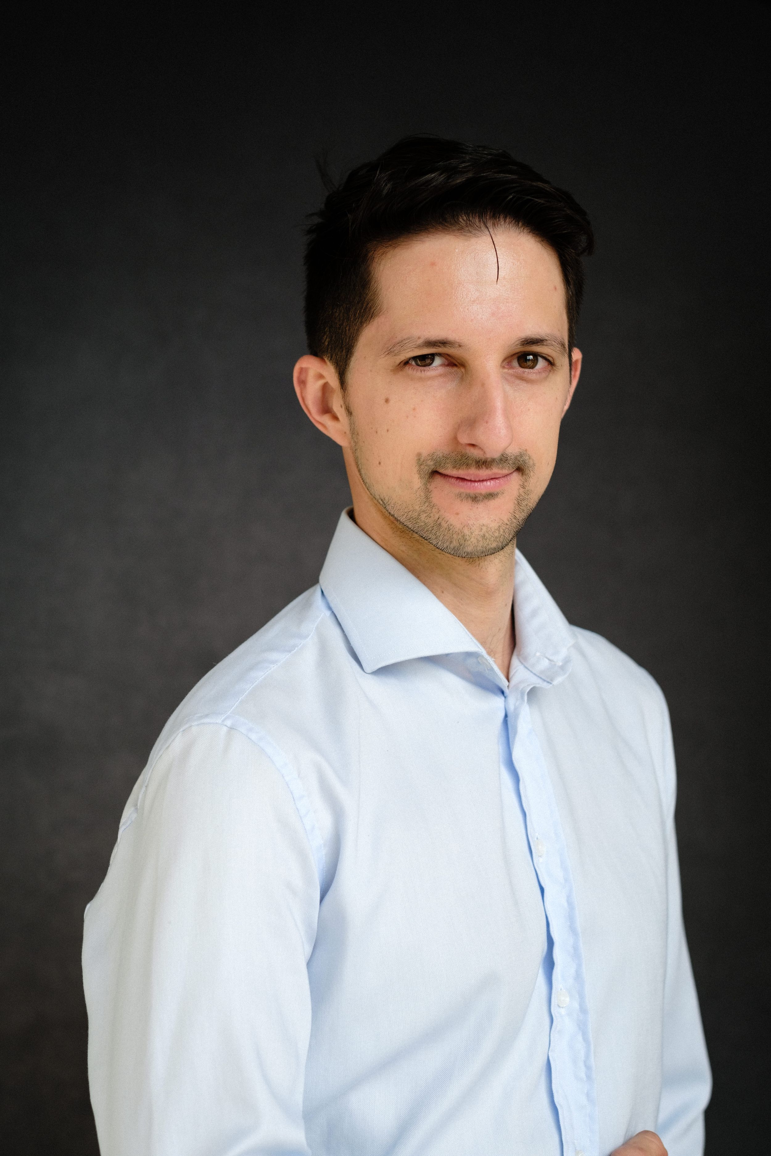 Professional studio portraits showing white button-down shirt against dark background.