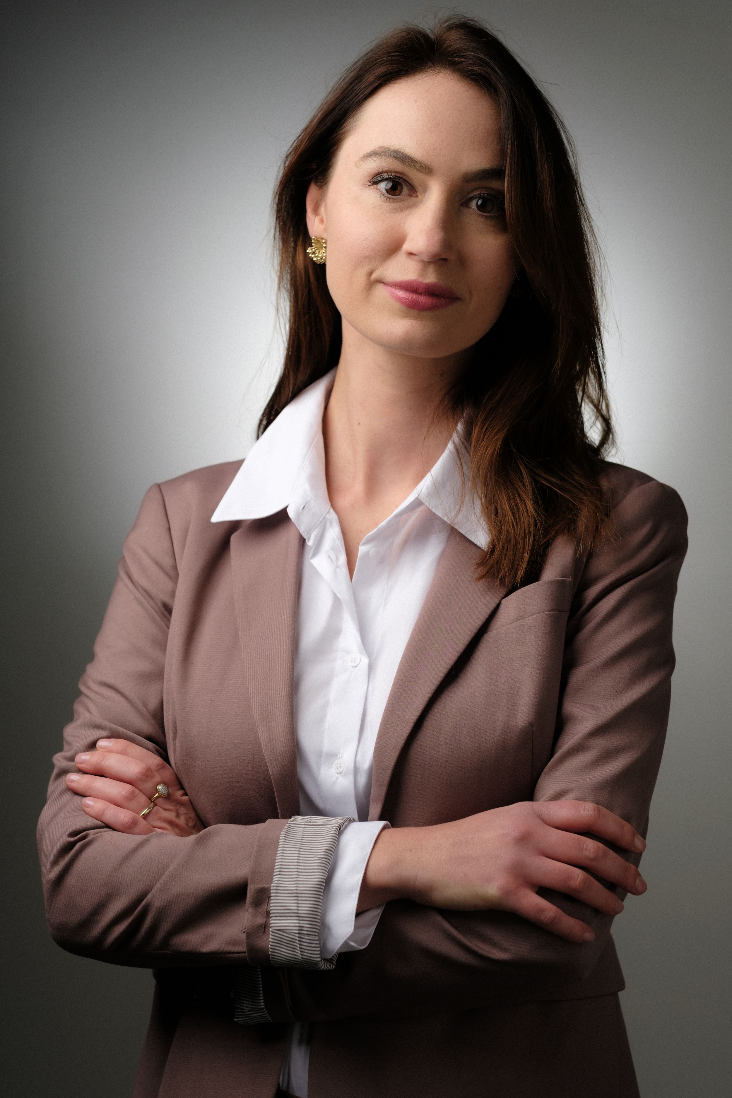 Business portrait series showing person in brown blazer and white shirt with crossed arms.