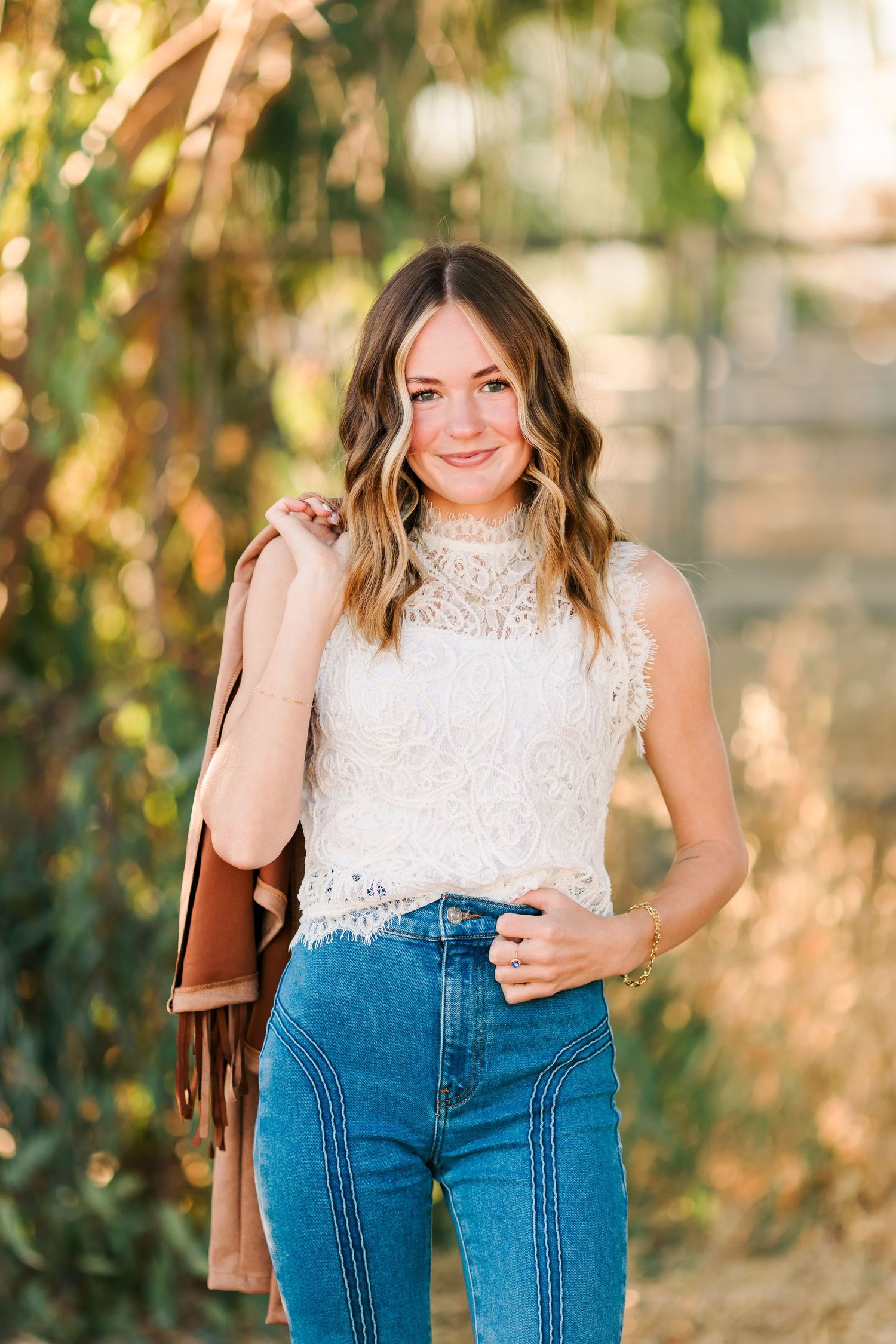 A white lace sleeveless top paired with high-waisted blue jeans creates a casual yet elegant summer outfit.
