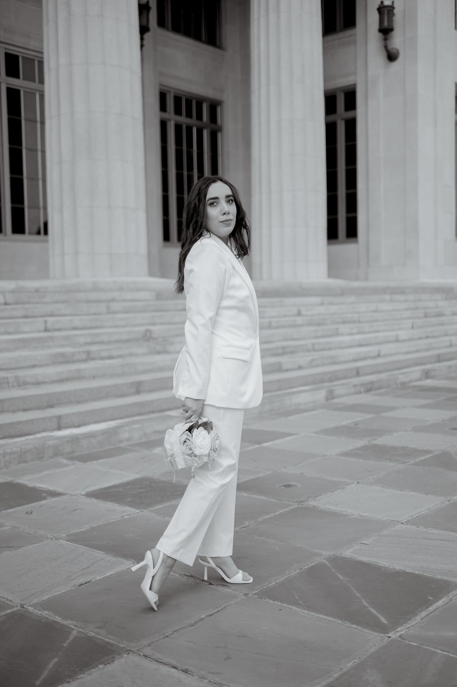 Black and white photo series showing someone in white attire walking across stone steps between classical pillars.