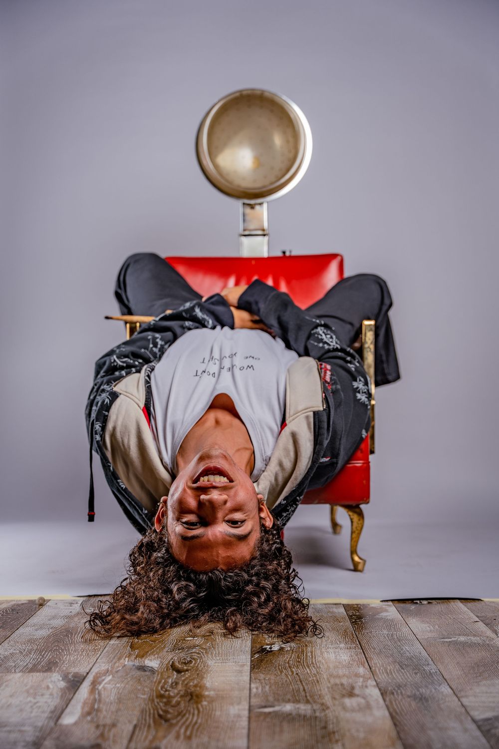 Creative upside-down portrait of person lying on red chair with vintage microphone.