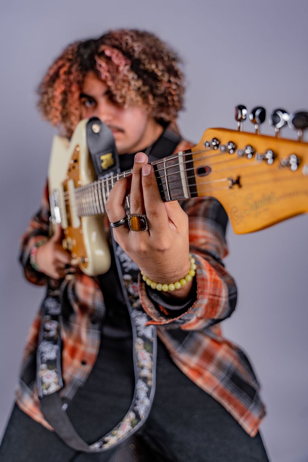 Close-up shots showing hands playing an electric guitar while wearing a plaid flannel shirt and black vest.