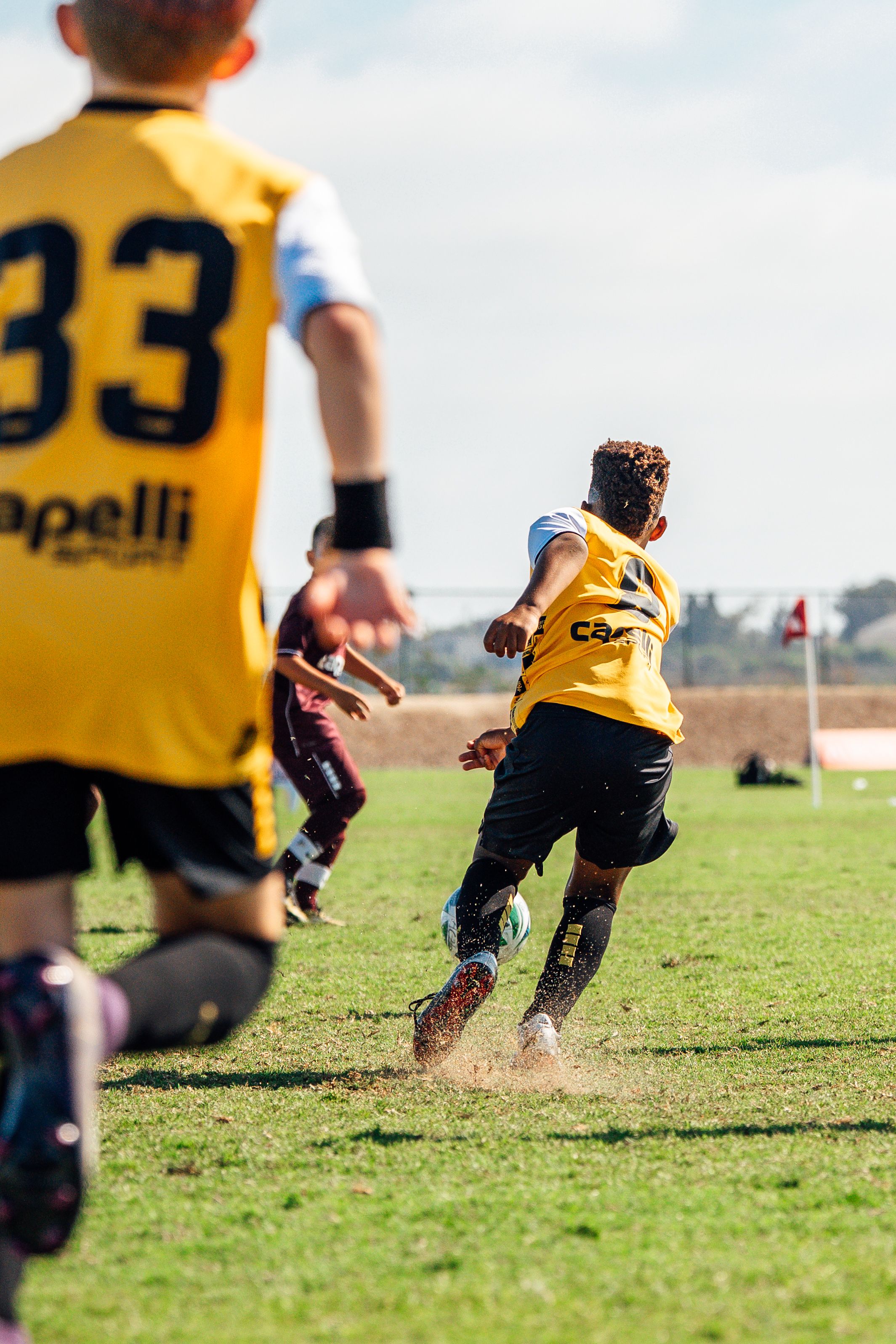 Soccer players in yellow jerseys running on grass field during practice.
