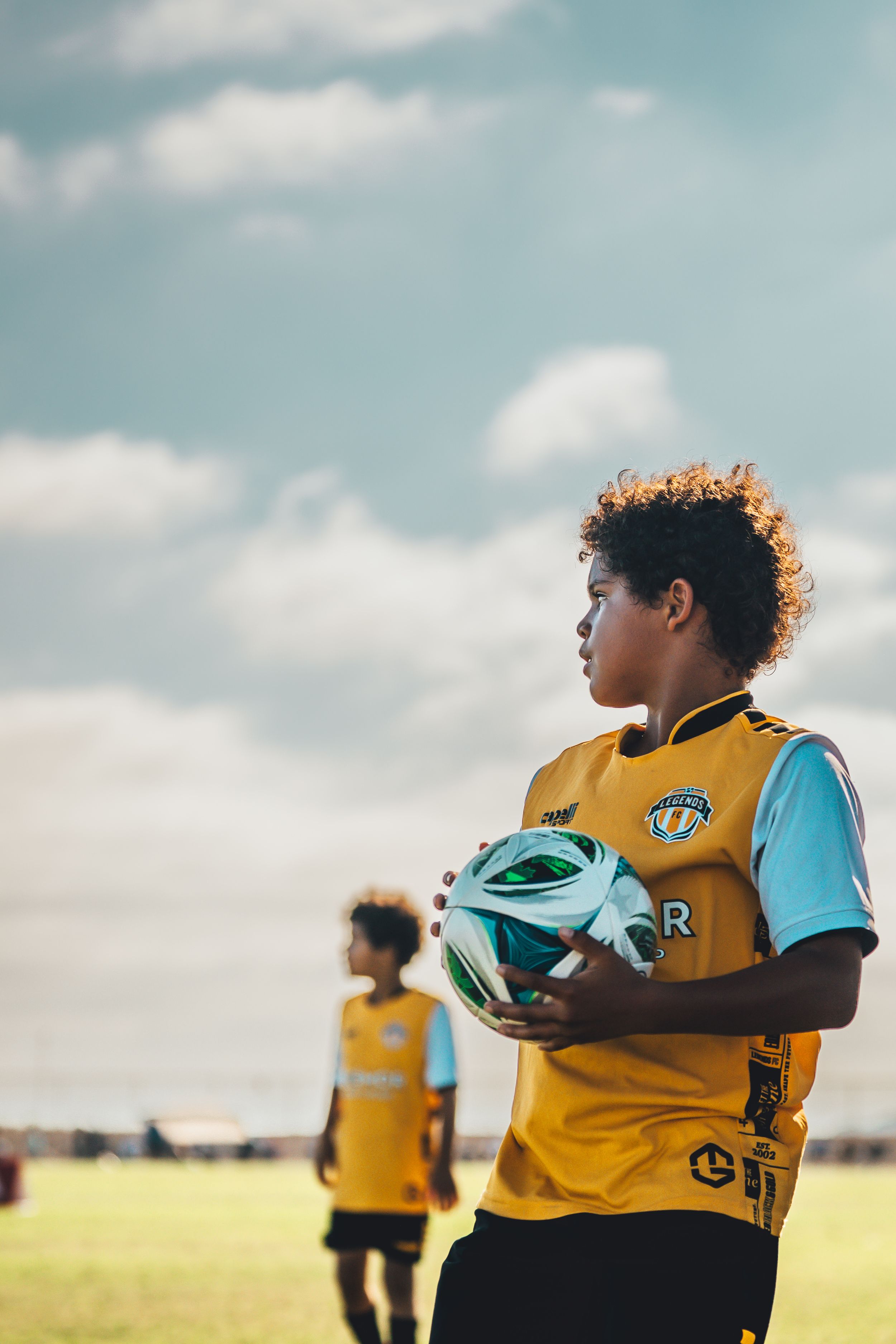 Soccer players in yellow and blue uniforms standing on sunny field.