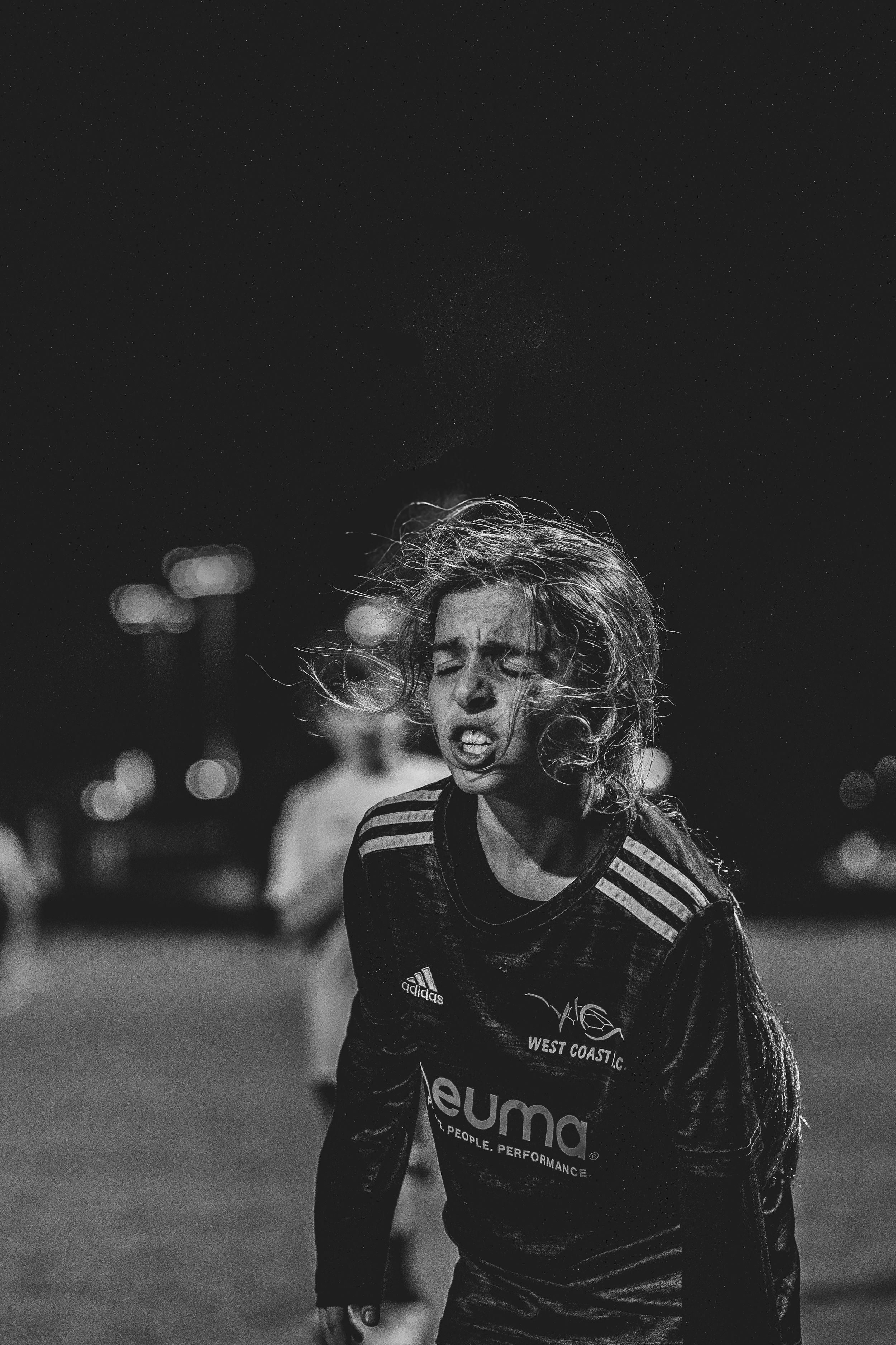Soccer player in black uniform with windswept hair running on field during intense game action.