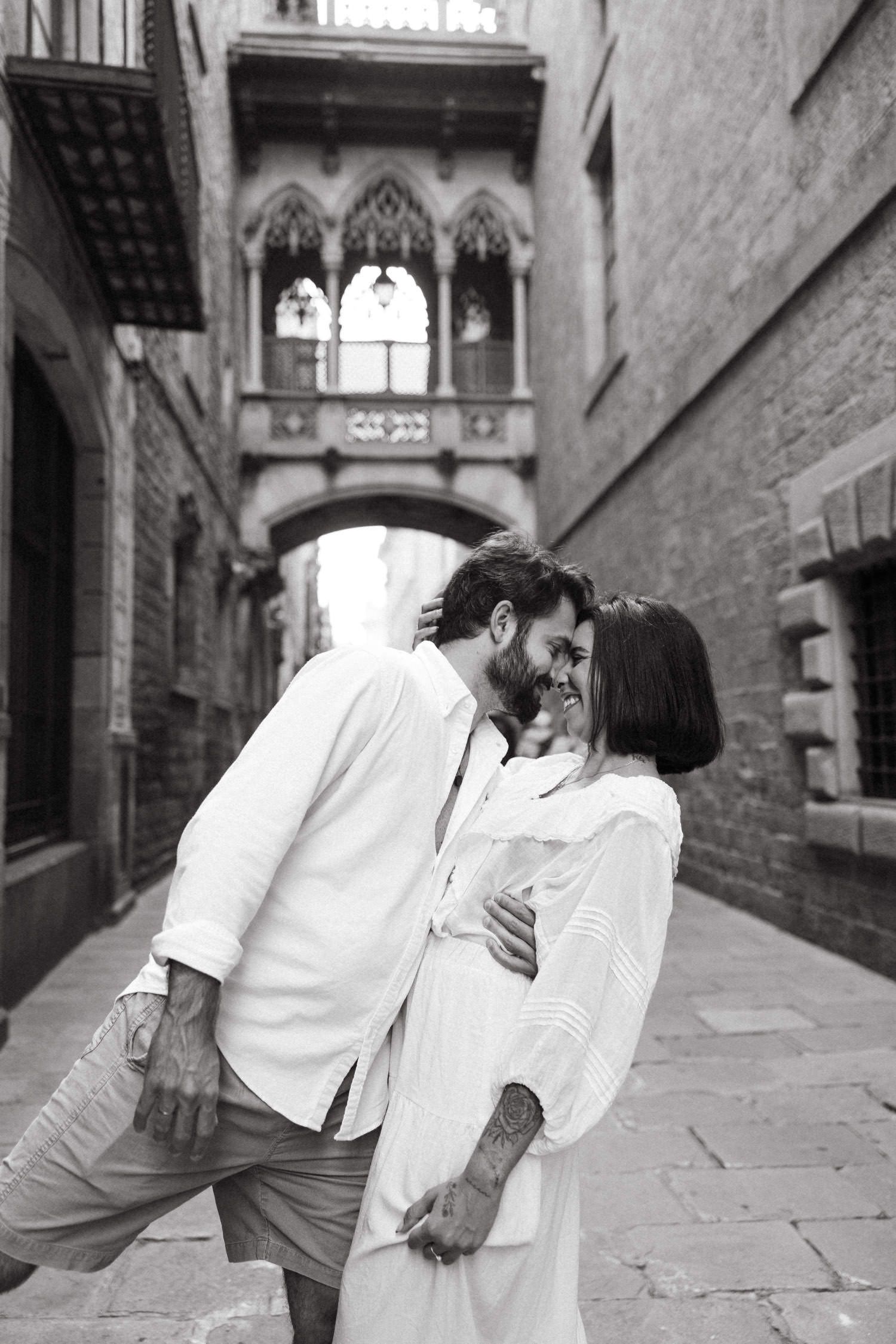 A couple in white clothing dances and embraces in a medieval stone corridor.