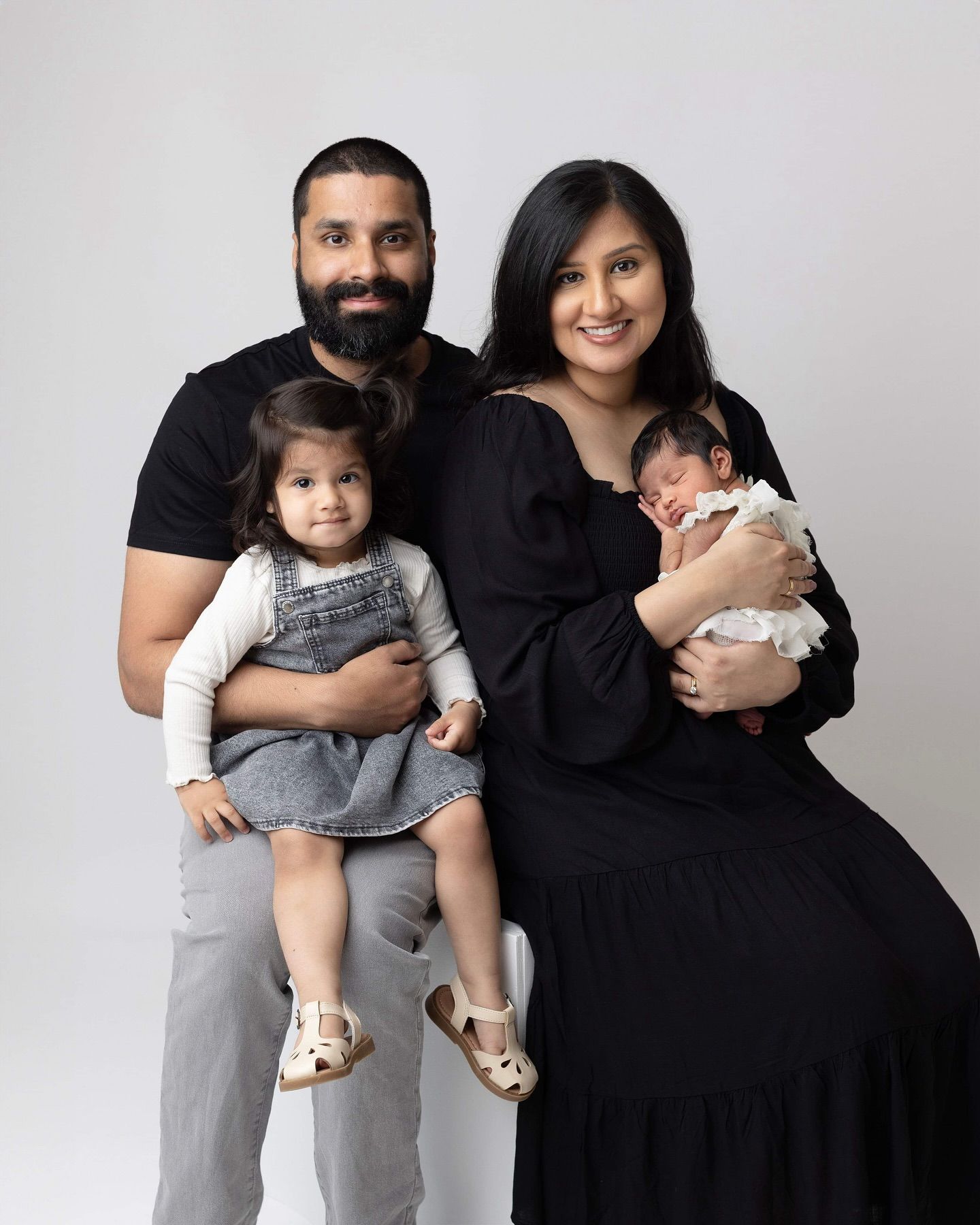 A family in black and gray clothing poses together showing their close bond in a series of progressive shots. Newborn Photo Studio Elizabeth