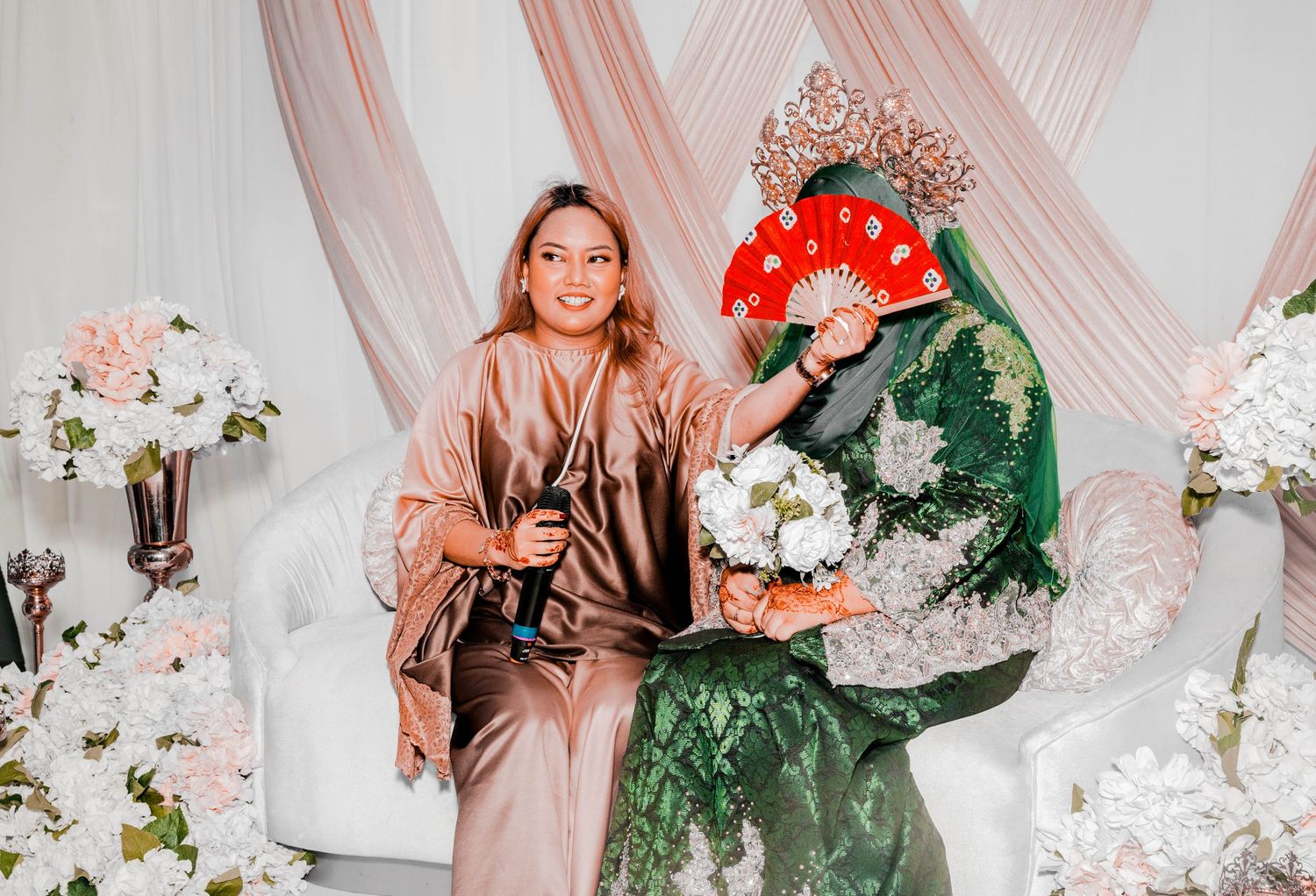 Wedding guests pose against pink draped backdrop with floral arrangements.