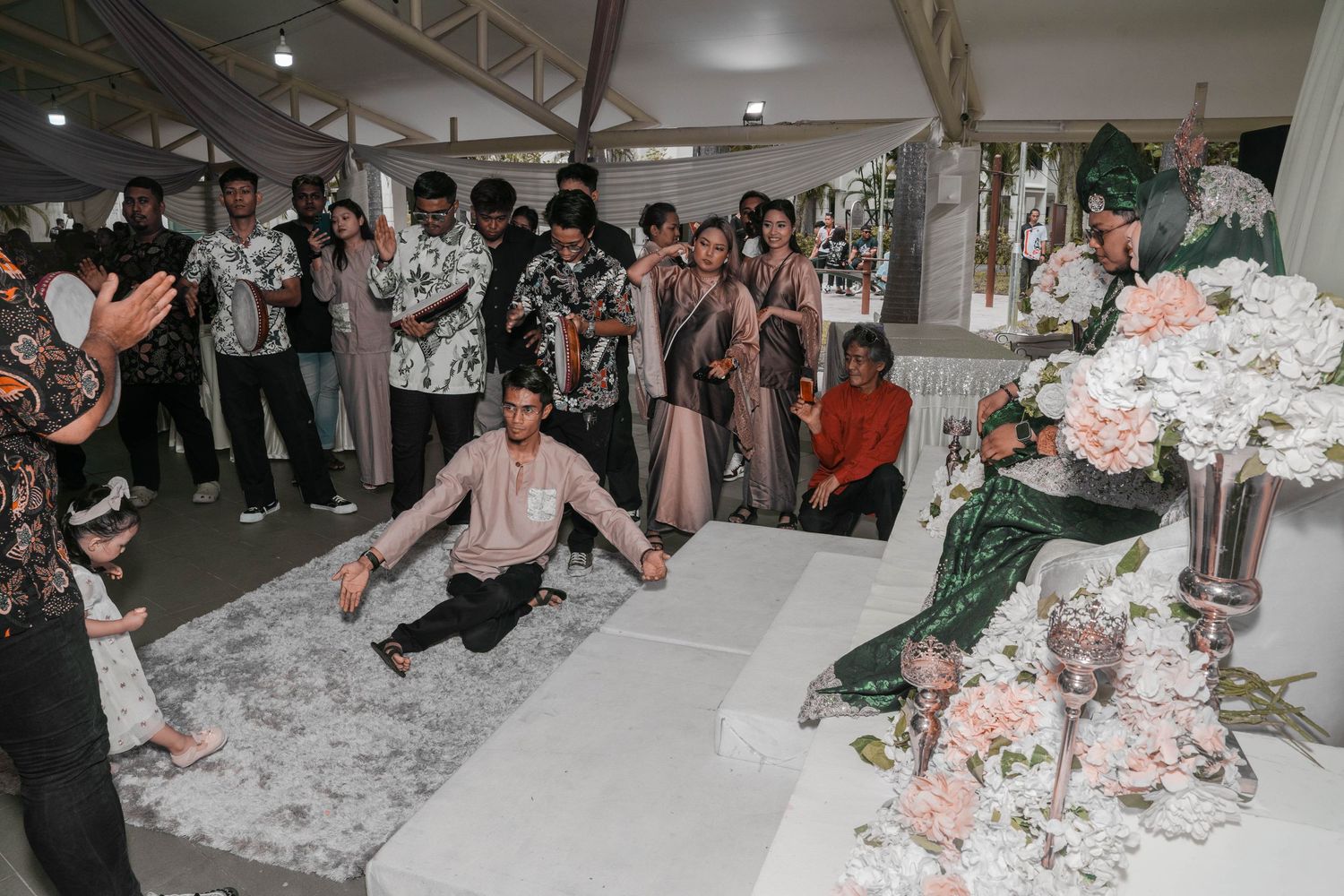 Wedding celebration with guests dancing and celebrating on marble floor with floral decorations.