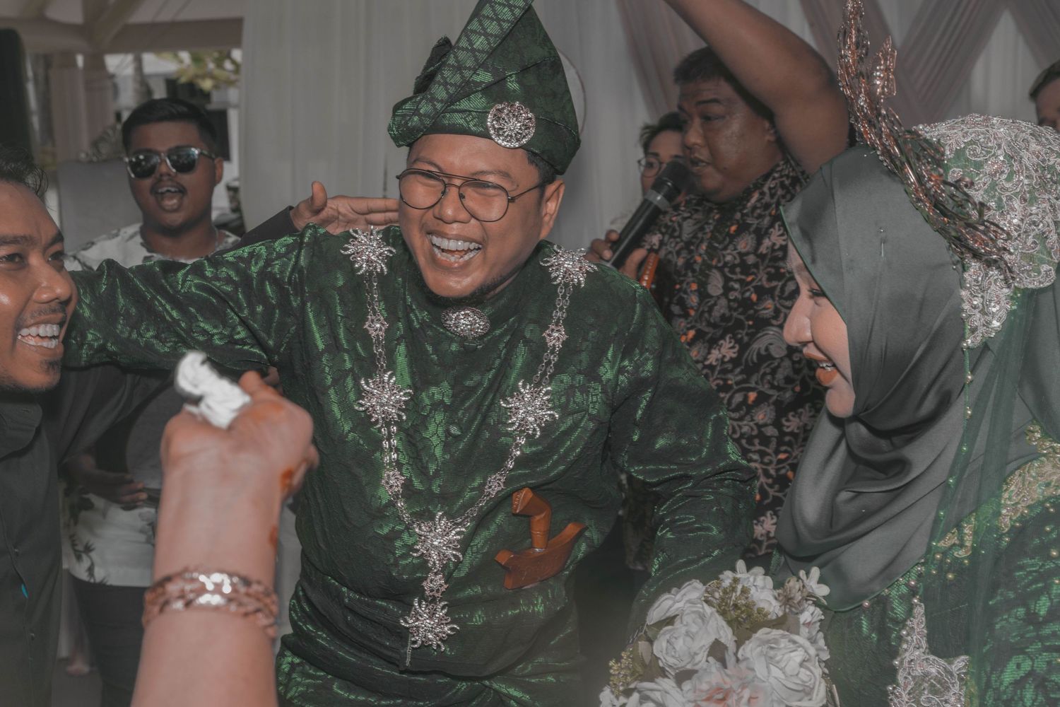 Wedding celebration with guests in festive green traditional attire.