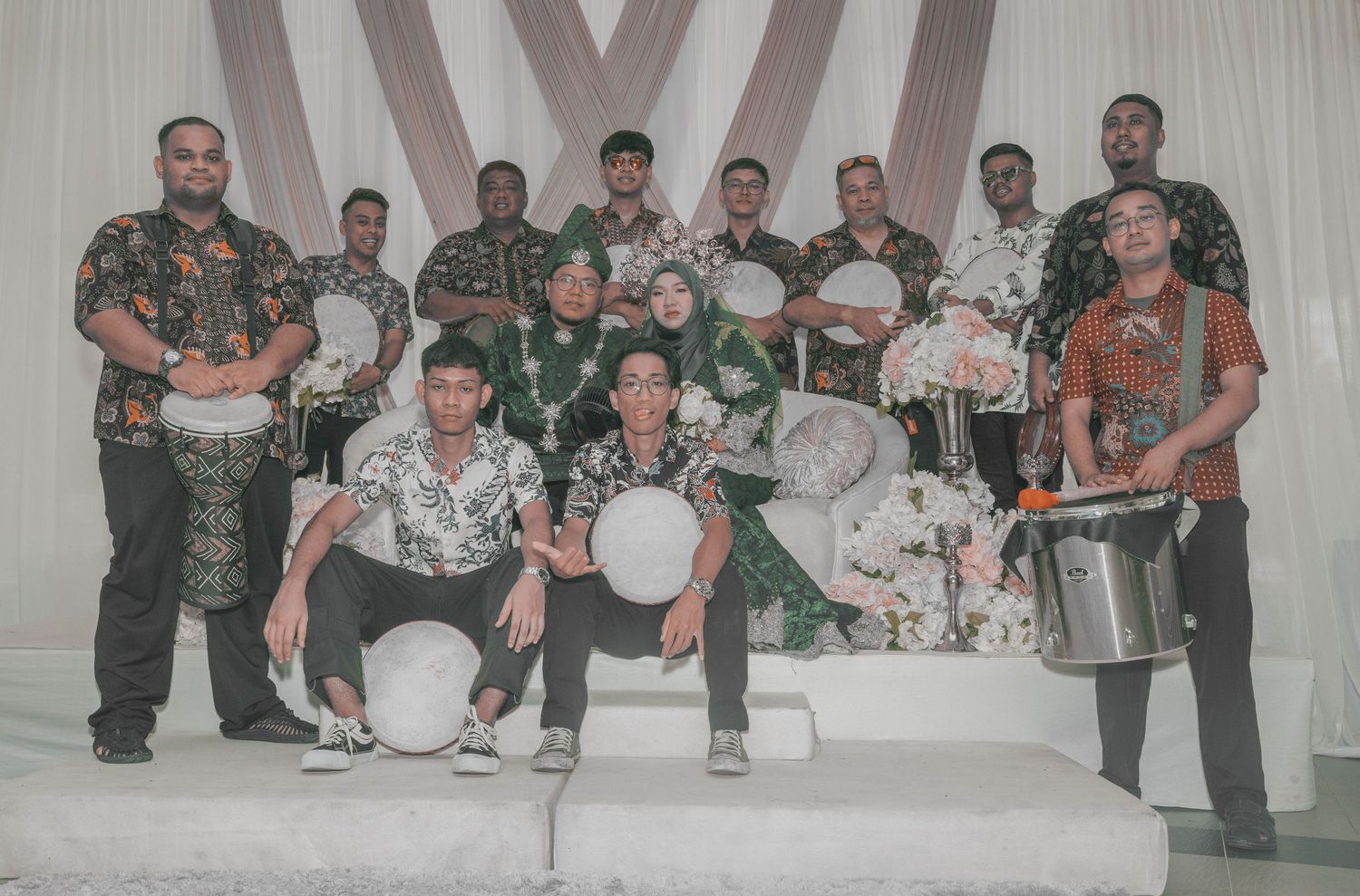 Group photo of percussion band members holding drums at wedding celebration.