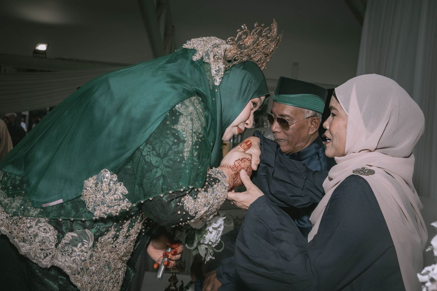 A close-up shot of someone wearing an emerald green lace dress with intricate embellishments during a celebratory moment.