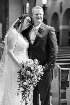 An intimate black and white portrait of a couple sharing a tender moment in a church.
