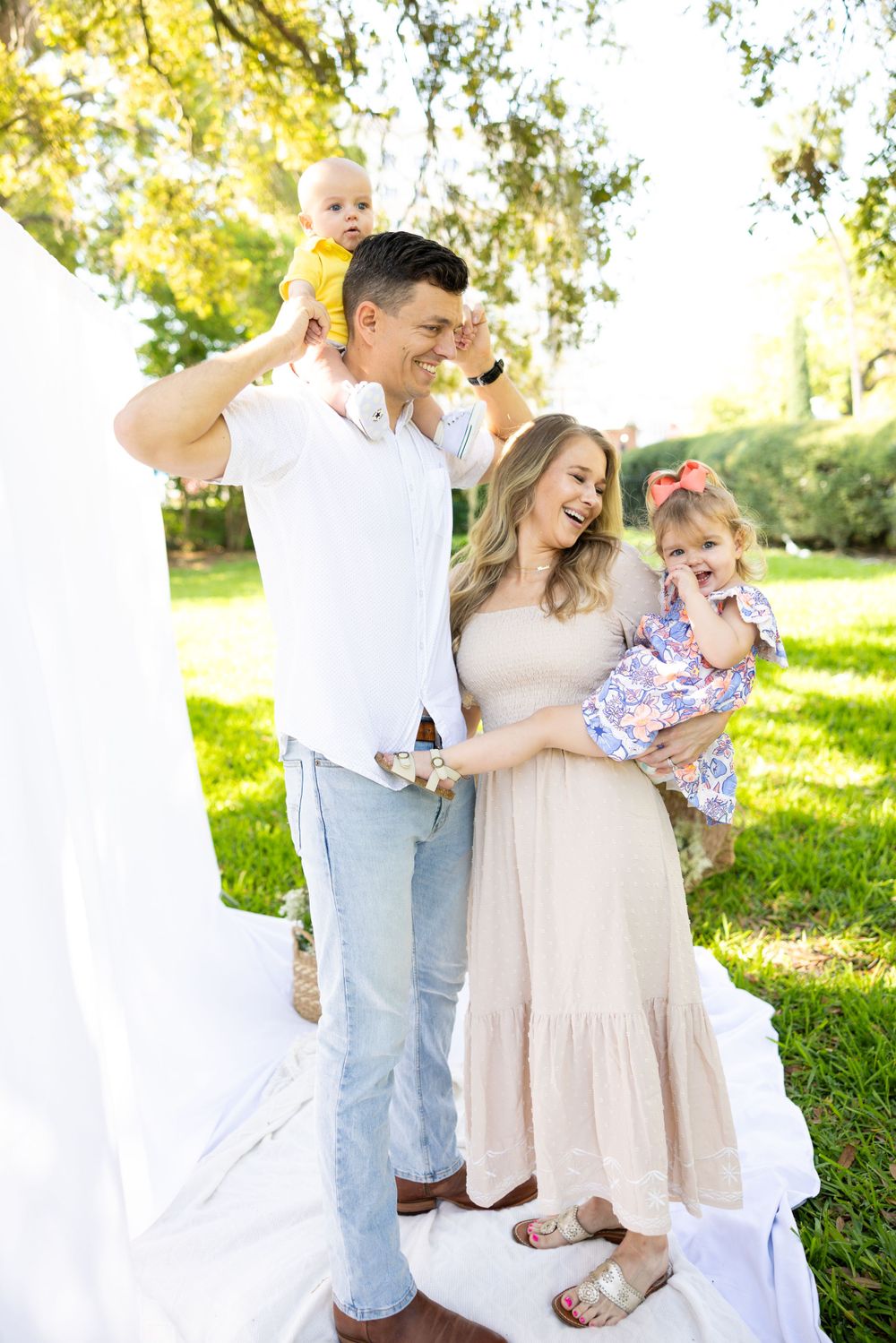 A family shares joyful moments together outdoors on a sunny day in a park setting.