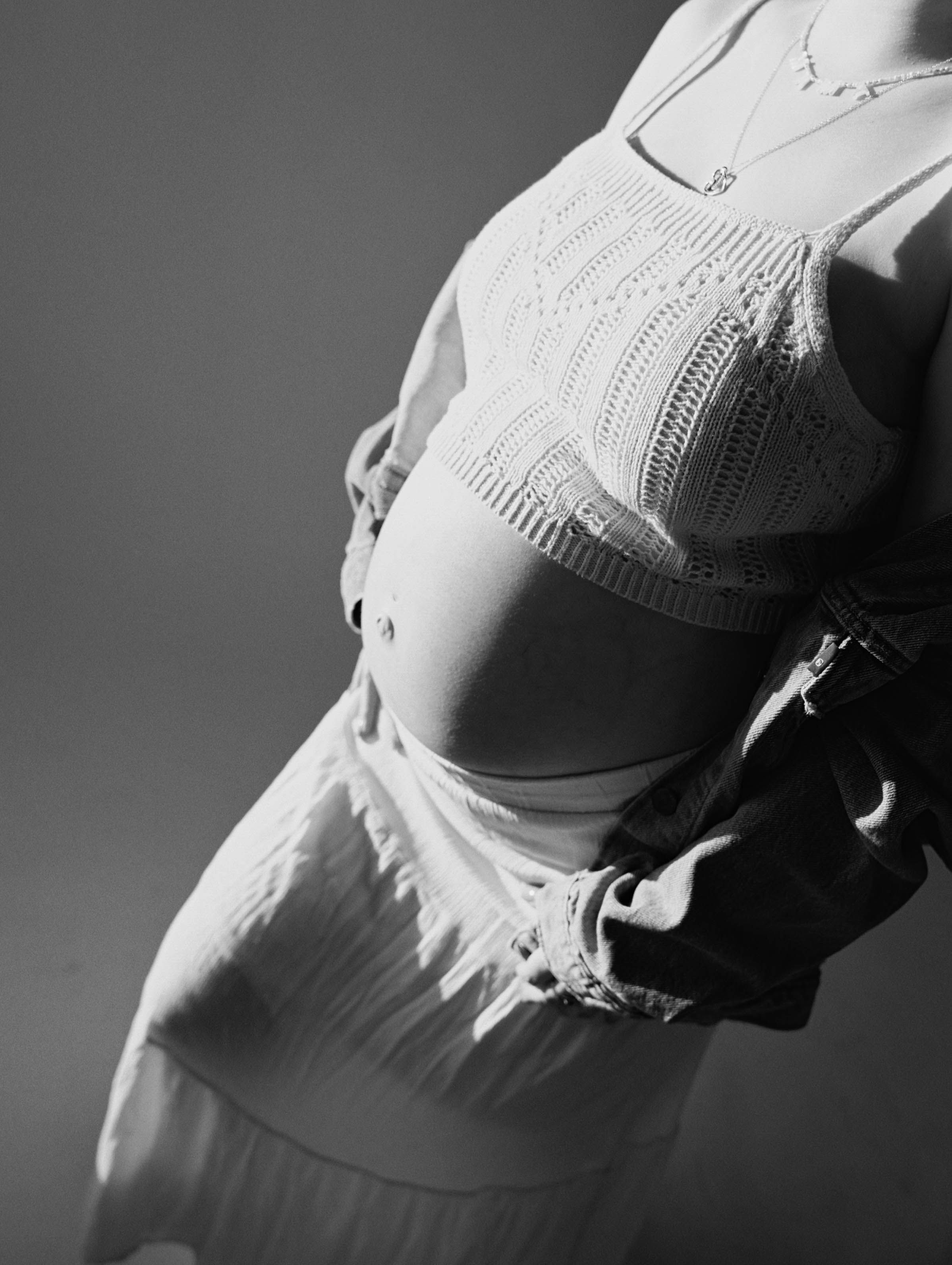 A black and white close-up of delicate white lace details on clothing.