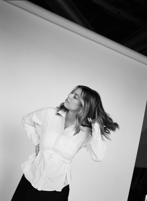 A model in a white button-up shirt twirls with dynamic movement against a stark white background in black and white.