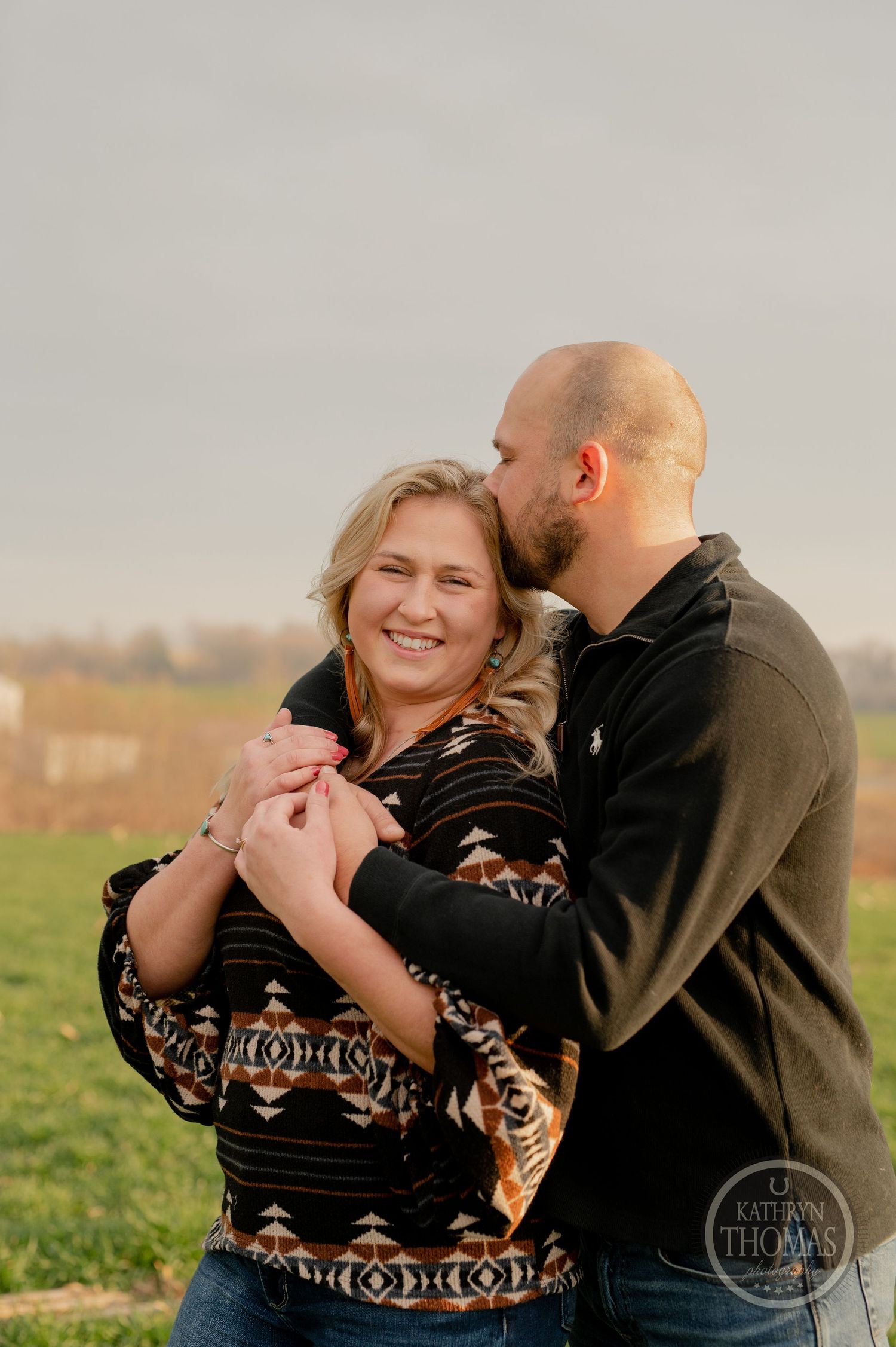A couple shares an intimate moment in an outdoor setting during sunset.