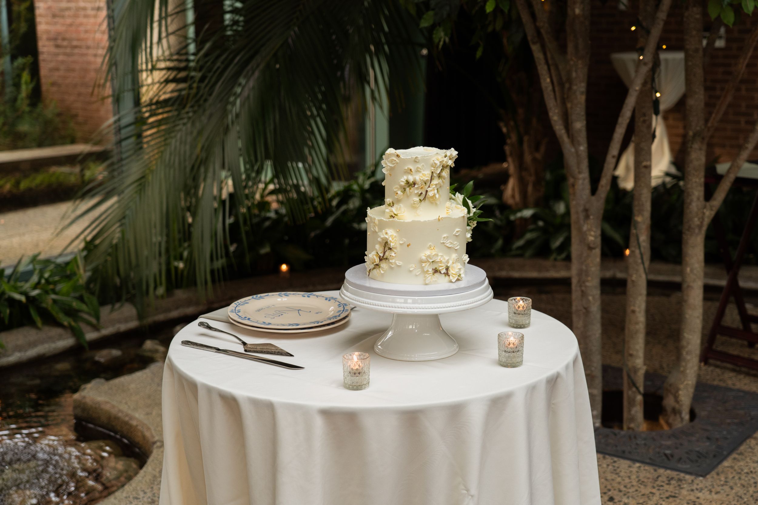 a wedding cake with greenery behind it at a botanical garden venue