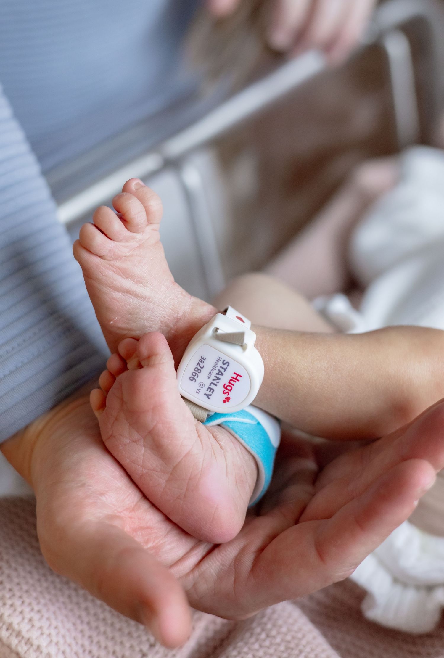 Parents sitting on floor of nursery with mint green walls holding their newborn baby.