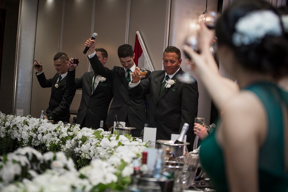 Group celebrates at elegant wedding reception with white floral decorations.