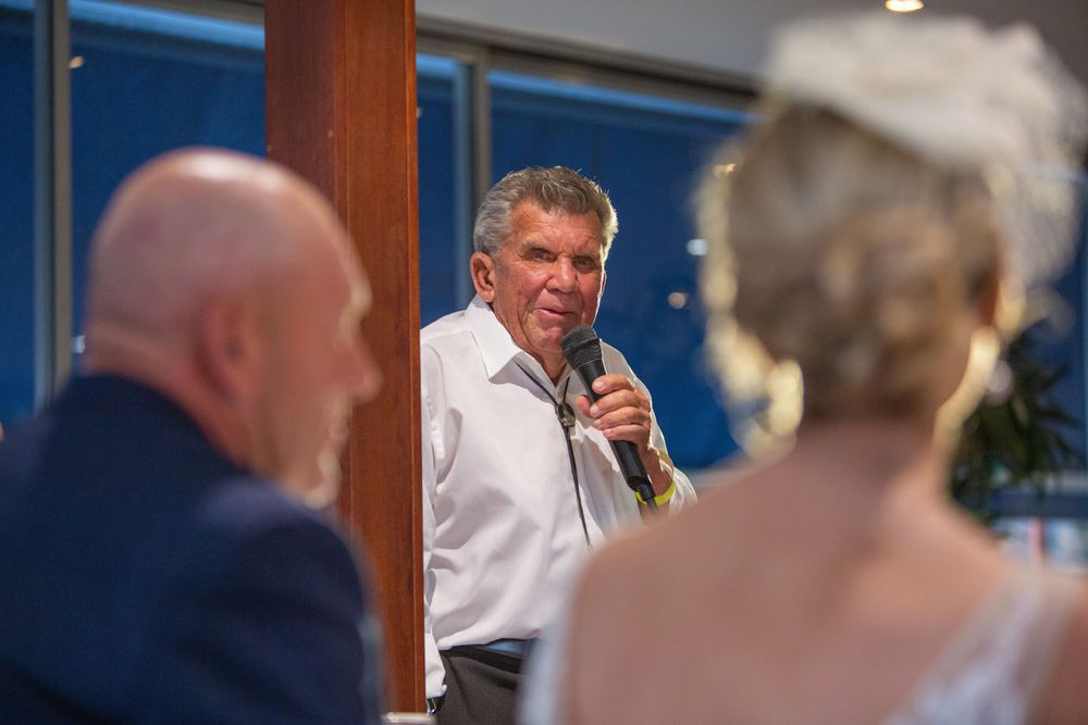 A speaker holding a microphone addresses attendees at an indoor event.