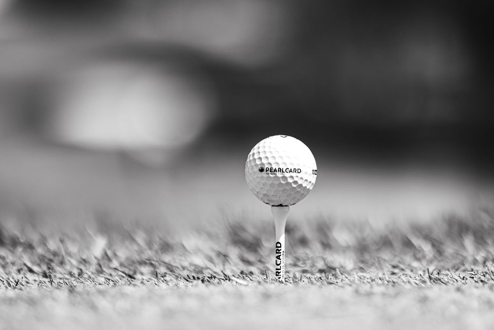 Golf ball on tee in black and white macro photography.