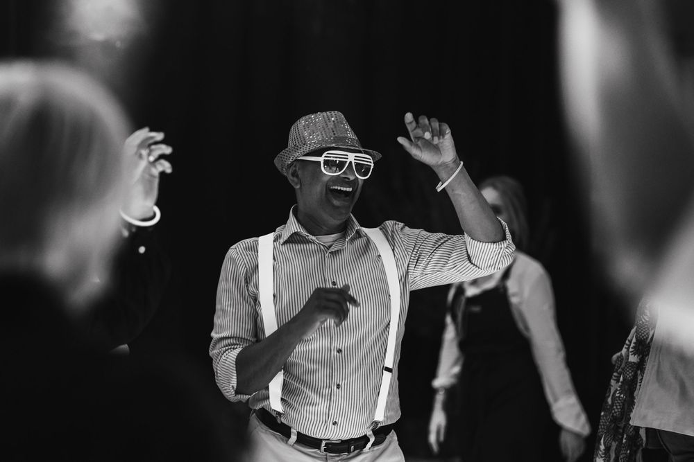 Black and white crowd scene with people gesturing and interacting in a dark environment.