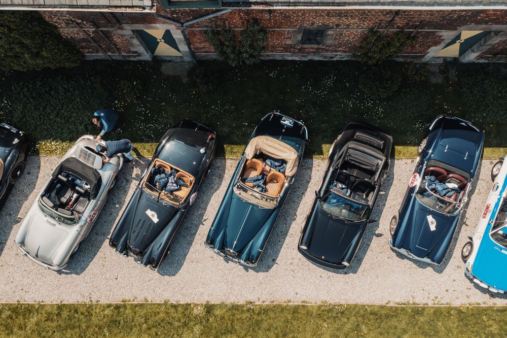 Aerial view of vintage cars parked in a row against a brick building.