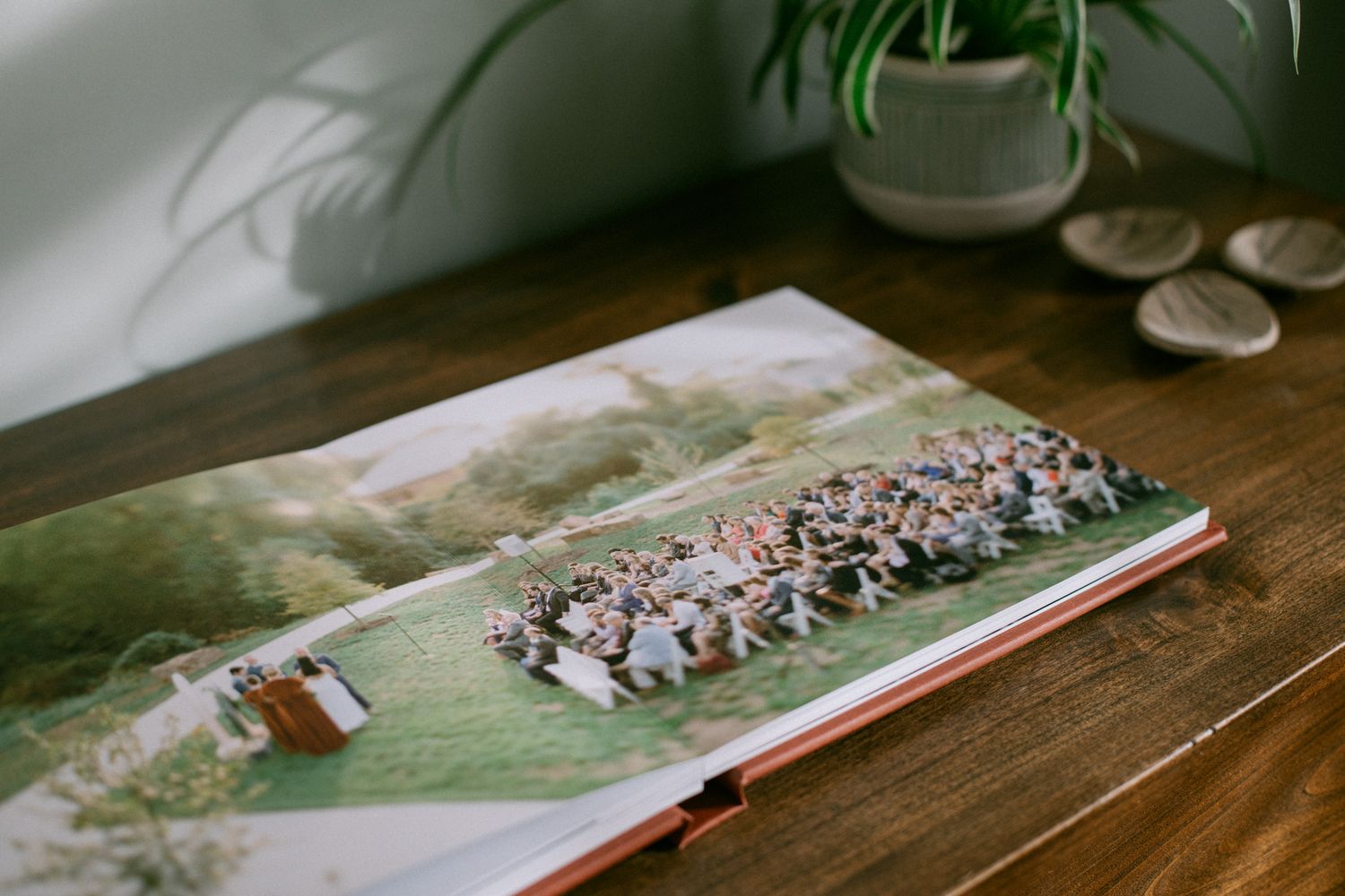 Wedding photo album showing a group photo spread on a wooden table with decorative elements.