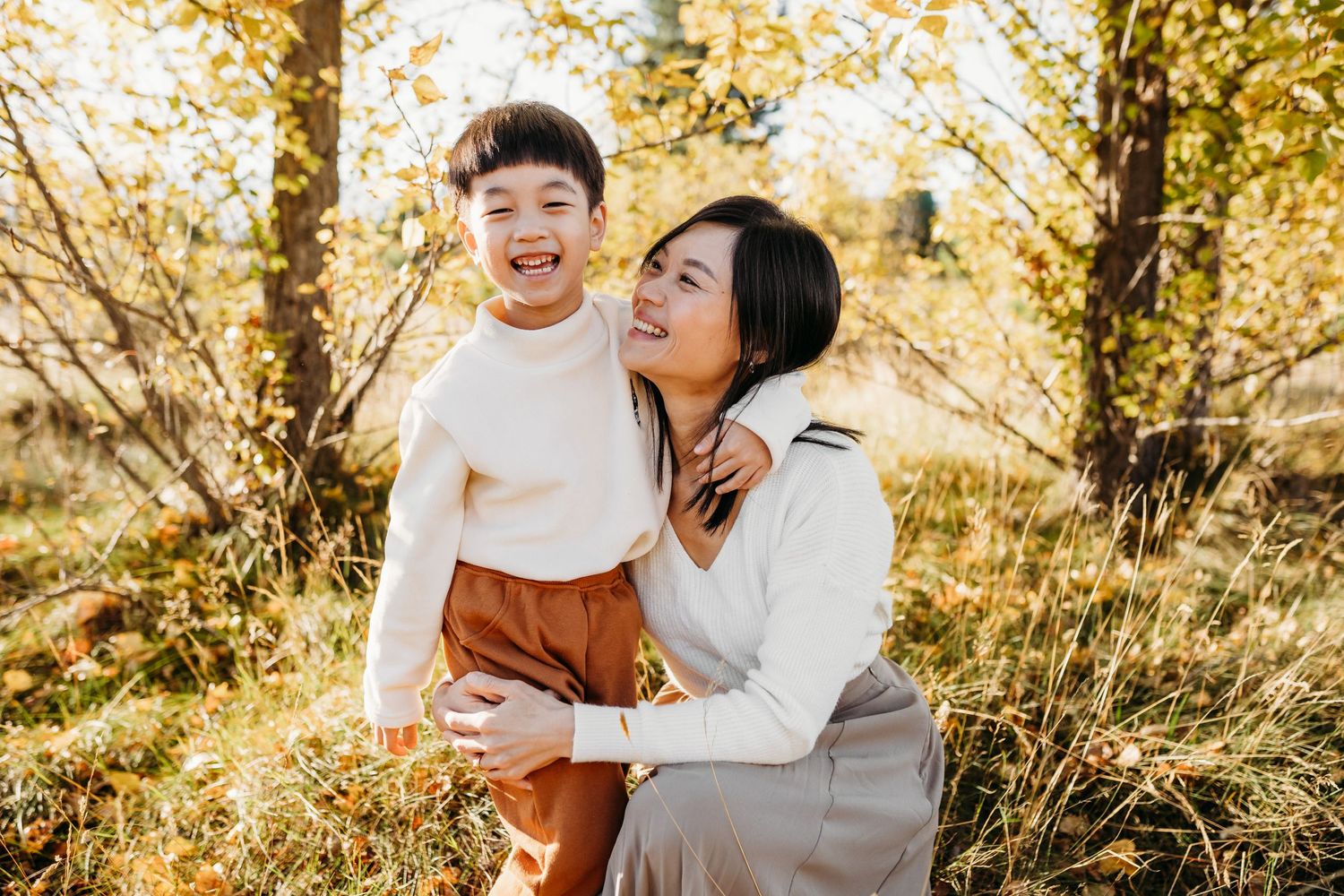 Mother and child sharing a warm, candid moment in golden autumn sunlight.