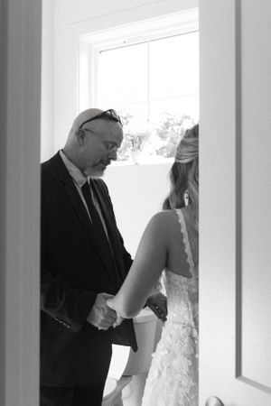 A black and white photo capturing a private moment in a bright doorway.