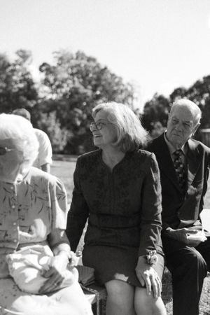 A black and white outdoor photograph showing people sitting together at a formal gathering.