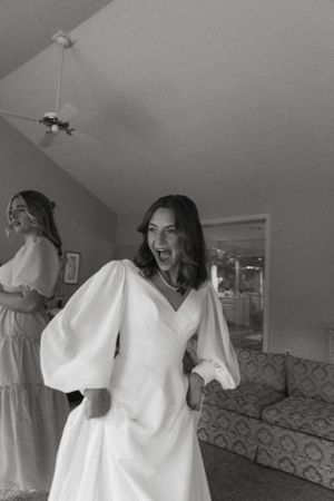 Black and white photo of a joyful woman in a white dress with balloon sleeves.