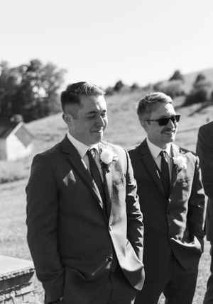 Black and white portrait of groomsmen in classic suits standing outdoors.