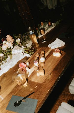 Wedding reception table with candlelit decor and floral arrangements on wooden surface.