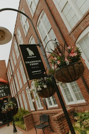 View of Craddock Terry Hotel entrance with hanging floral baskets and branded sign against brick facade.