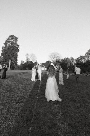 Black and white photo of wedding guests gathered on a grassy hillside.