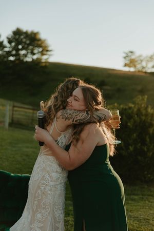 Emotional sunset embrace between two people at an outdoor wedding reception.