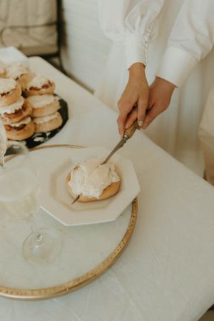 Hands cutting into cream-topped dessert at elegant wedding reception.