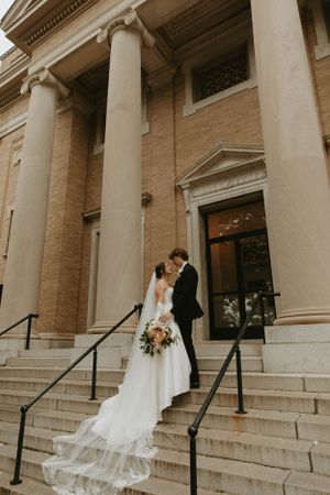Couple sharing a romantic moment on grand stone steps of a classical building.