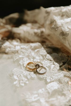 Wedding rings placed on delicate white lace fabric in closeup detail shot.