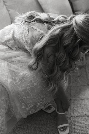 Black and white detail of intricate lace wedding dress and flowing hair.