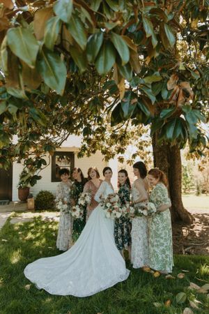 Wedding party gathered under a magnolia tree on a sunny day.