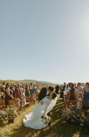 Romantic outdoor wedding ceremony with mountain backdrop and flower-lined aisle.