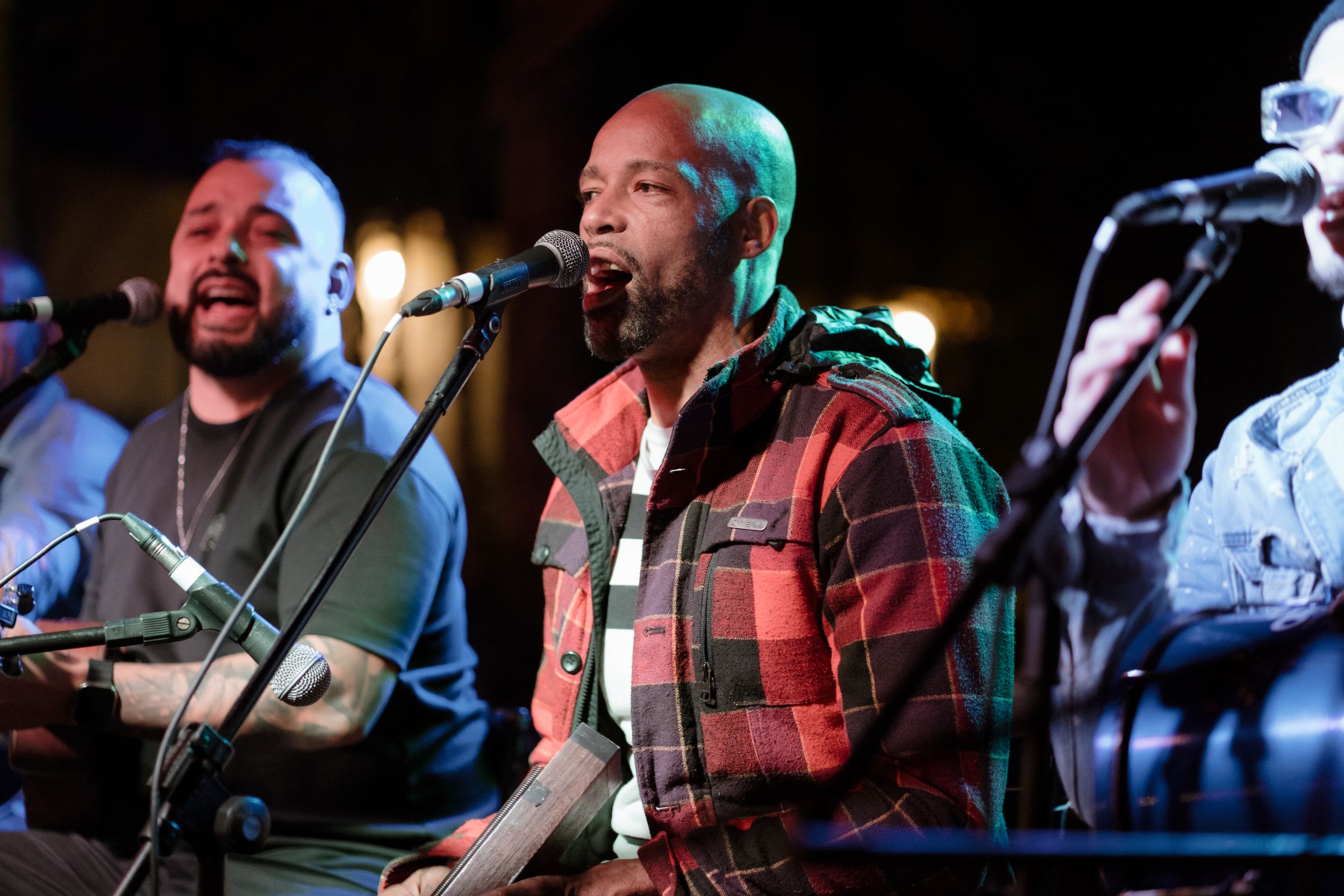 Musicians perform on stage under colorful lighting at night.