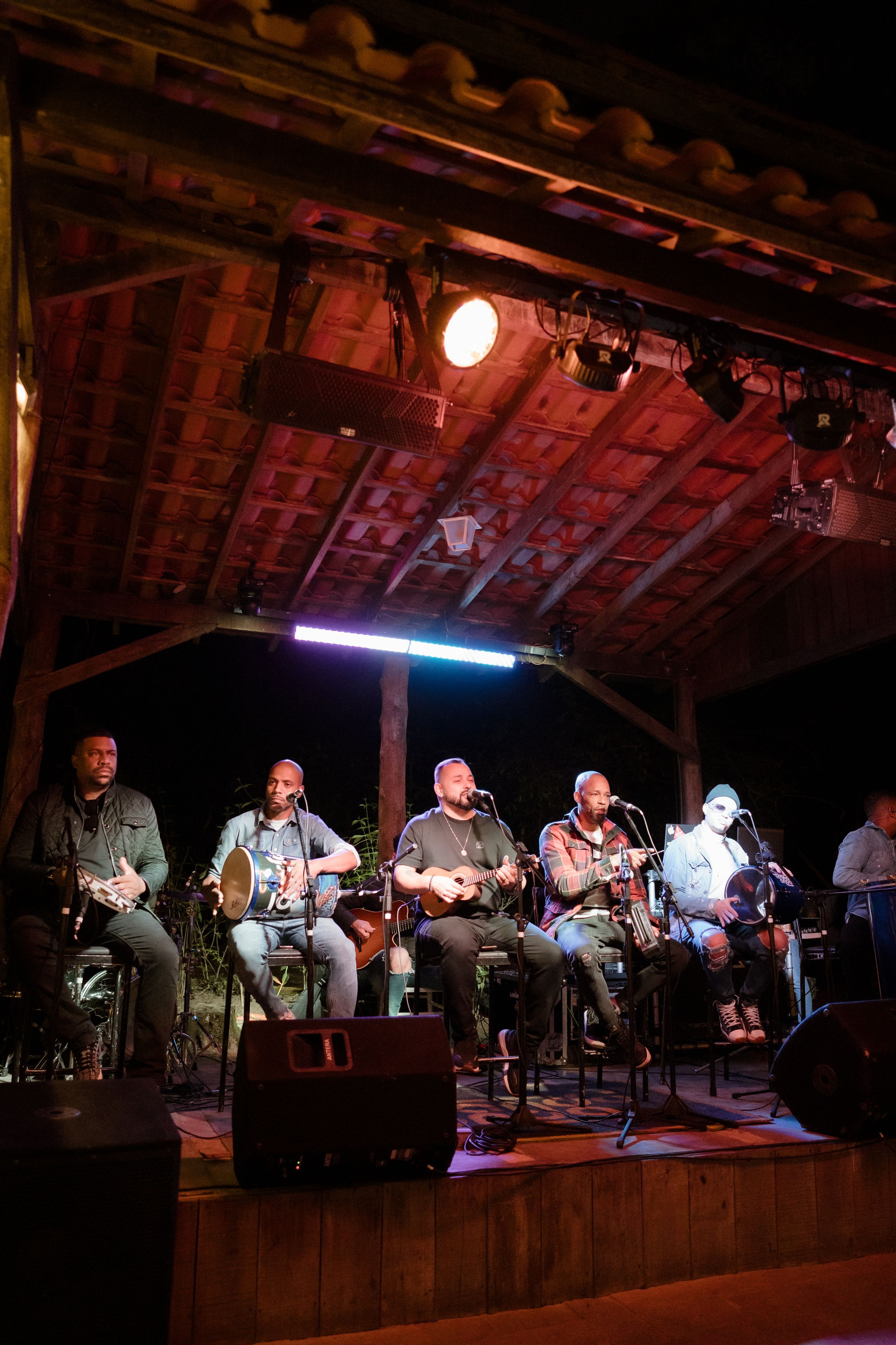 Band performs on wooden stage under dramatic red lighting and exposed beam ceiling.