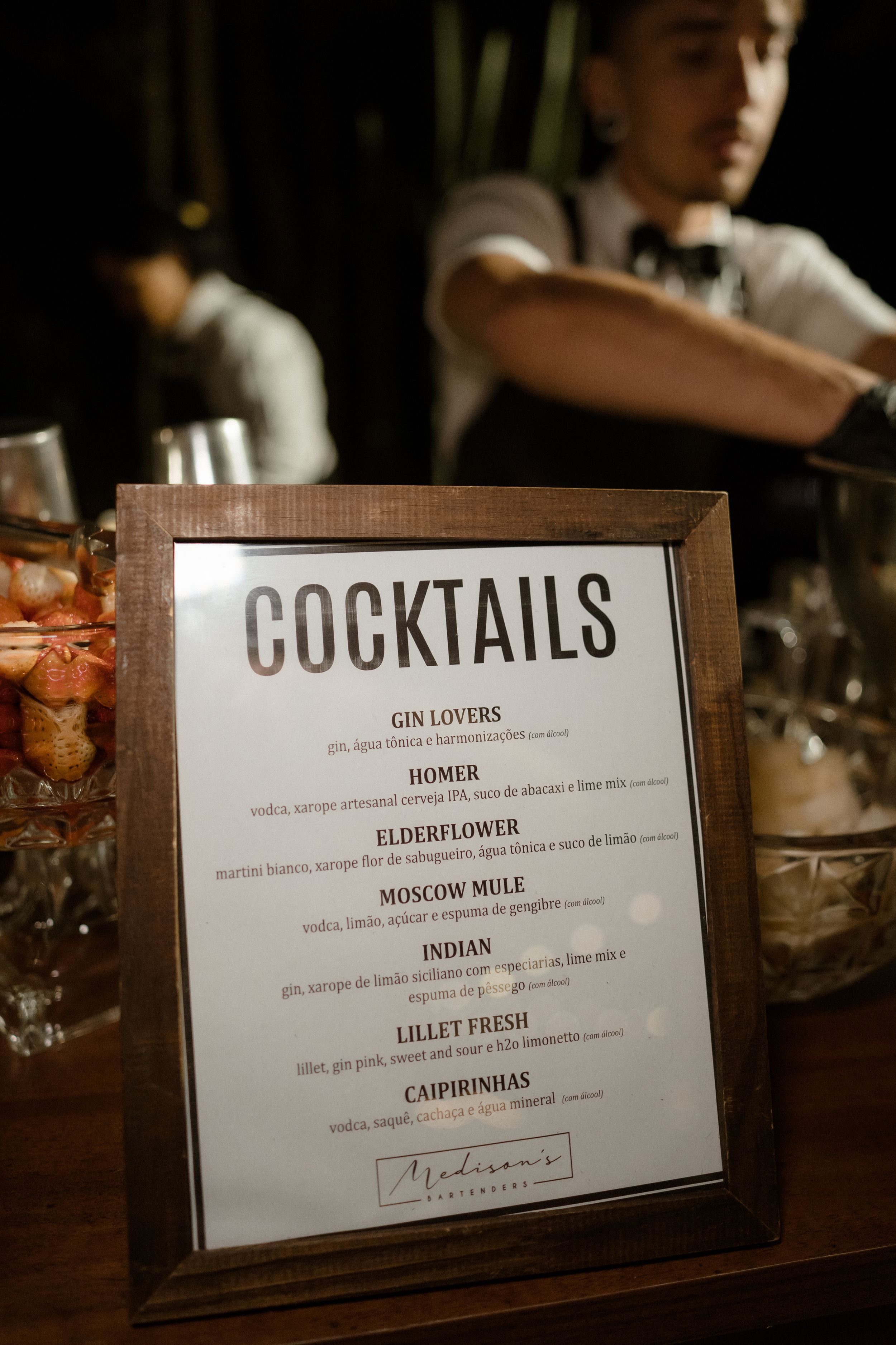 Close-up shots of a cocktail menu on a wooden table showing drink names and descriptions in warm lighting.