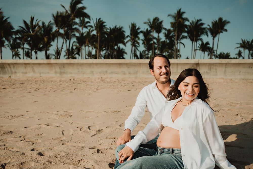 Smiling at the camera, capturing the joy of this Mazatlán pregnancy session by the beach